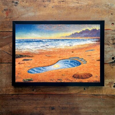 Quadro horizontal emoldurado com pintura de uma praia ao entardecer, com uma pegada gigante marcada na areia laranja e o mar ao fundo.