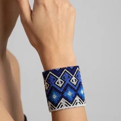 Pulseira indígena de miçanga azul e branca larga, losangos Wixárika em tons de azul, usada no pulso